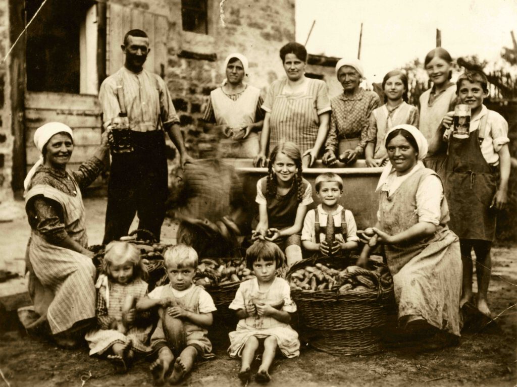 Auf dem Bild ist eine Gruppe Menschen zu sehen. Es ist ein altes Bild in Sepia.